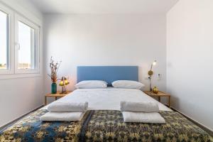 biała sypialnia z dużym łóżkiem z niebieskim zagłówkiem w obiekcie Livemálaga Victoria Suites w Maladze