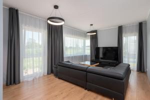 sala de estar con sofá de cuero negro y TV de pantalla plana en Ladva 10, en Tartu