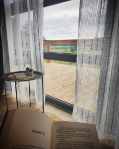 a book sitting on a table in front of a window at Mazury Holiday Cottage in Piecki