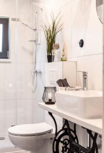 a white bathroom with a toilet and a sink at Mazury Holiday Cottage in Piecki