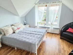 a bedroom with a bed and a chair and two windows at Family Hotel in Daugavpils
