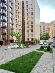 due alberi in un cortile di fronte agli edifici di Sweet Home a Dnipro