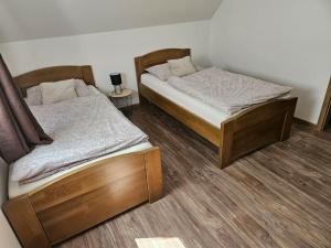 two twin beds in a room with wooden floors at Vinohradnícky domček in Vrádište