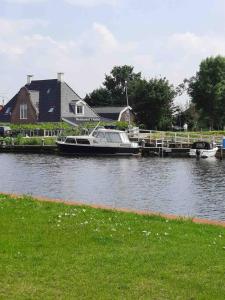 a boat is docked at a dock in the water at Suite met eigen douche, toilet, kitchenette in Kolhorn