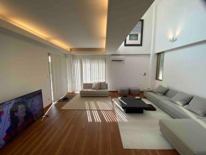 sala de estar con sofá y TV de pantalla plana en Vacation Rental Kally Naha Okinawa, en Naha