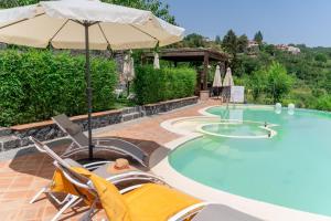a swimming pool with two chairs and an umbrella at Etna Sunshine Rent Rooms in Puntalazzo