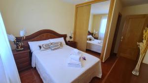 a bedroom with a bed with towels and a mirror at Las Golondrinas de Henche in Henche