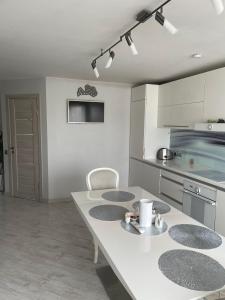 a kitchen with a white table with four chairs at Emporium Apartments in Rēzekne