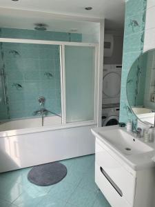 een badkamer met een bad, een wastafel en een spiegel bij Emporium Apartments in Rēzekne
