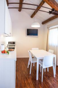 una cucina e una sala da pranzo con tavolo e sedie bianchi di Residenze Di La' Dal Fiume a Caorle