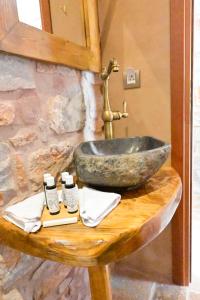 a bathroom with a stone sink on a wooden table at Arapis Rooms & Suites in Áyios Kiprianós