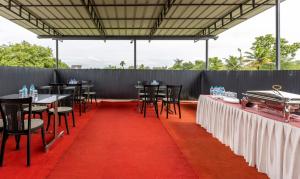 une salle de banquet avec des tables et des chaises sur un tapis rouge dans l'établissement Treebo Trend Dreams Arcade, à Angamaly