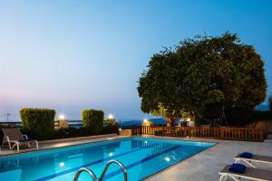 a swimming pool with chairs and a tree at Villa Eleftherna in Elefterna