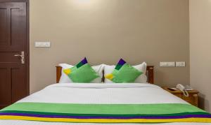- un lit avec des draps et des oreillers verts et blancs dans l'établissement Treebo Trend Dreams Arcade, à Angamaly
