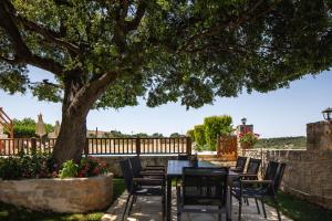 a patio with a table and chairs under a tree at Villa Eleftherna in Elefterna