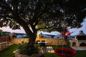 a tree in a yard with a table and a swing at Villa Eleftherna in Elefterna