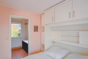 a bedroom with a bed and white cabinets and a window at Ferienhaus Bobby in Stahlbrode