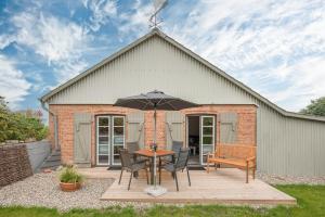 een patio met een tafel en stoelen en een parasol bij De ole Schaapstall in Dagebüll