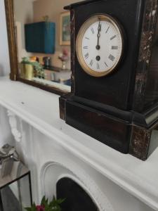 a clock sitting on a mantle in front of a mirror at Dibney Rig in Killyleagh