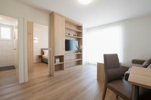 Smart & Stay Aparthotel Saarlouis Lisdorf - Self-Check-In - Free Parking في سارلويس: غرفة معيشة بها أريكة وتلفزيون في غرفة
