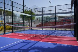 a tennis court with a net in a parking lot at Càmping Vila Village in Sant Feliu de Buixalleu
