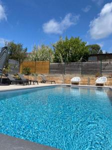 une grande piscine avec deux chaises dans l'établissement Gîtes de Lauvergnac - Maisons 2 Ch, 2 SdB, à La Turballe