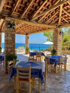 a patio with tables and chairs and the ocean at De La Plage Hotel Koroni in Koroni