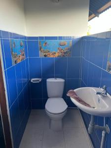 Baño de azulejos azules con aseo y lavamanos en Casa Colibri, en Nuquí