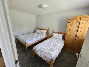 a bedroom with two beds and a wooden cabinet at T & J Motel in Lamberhurst
