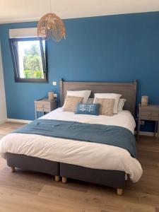 Gîtes de Lauvergnac - Maisons 2 Ch, 2 SdB في لا توربال: غرفة نوم بسرير كبير بجدار ازرق