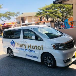 une camionnette blanche garée à côté d'un bâtiment dans l'établissement Diary Hotel, à Dar es Salaam