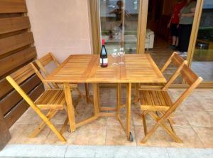 a wooden table and chairs with a bottle of wine on it at Planta baja con jardín en Llívia in Llivia