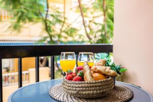 einen Korb mit Obst und Gemüse und zwei Gläsern Orangensaft in der Unterkunft Sur Suites Principe in Fuengirola