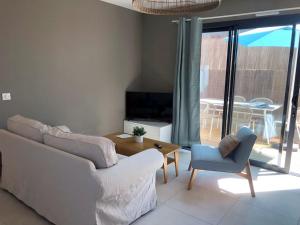 ein Wohnzimmer mit einem Sofa, einem Tisch und einem TV in der Unterkunft Gîtes de Lauvergnac - Maisons 2 Ch, 2 SdB in La Turballe