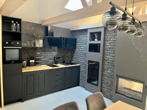 a kitchen with black cabinets and a brick wall at Clockhouse Cottage in Saulkrasti