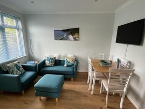 a living room with a blue couch and a table at SunnyVale Valley View Cottage in Gorran Haven