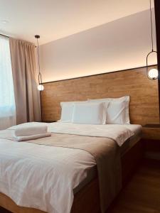 ein Schlafzimmer mit einem großen Bett mit weißer Bettwäsche und Kissen in der Unterkunft CentralLuxuryAptHotel in Piatra Neamţ