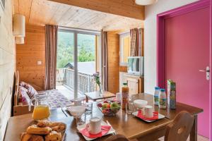 een eetkamer met een tafel met eten erop bij Lagrange Vacances Le Domaine des 100 Lacs in Cauterets