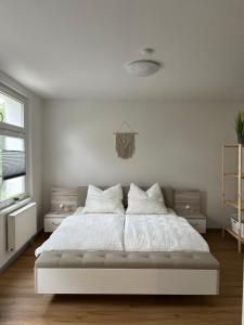 een slaapkamer met een wit bed met witte lakens en kussens bij Gemütliche und moderne Ferienwohnung in der Innenstadt in Pasewalk