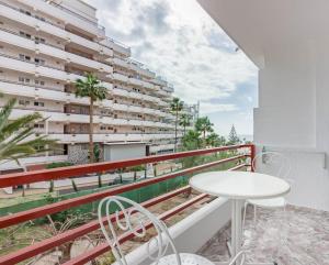 a balcony with a white table and chairs and a building at TENERIFE Olympia Apart Hotel-Playa de las Americas. Balcony, sea view & pool in Playa de las Americas