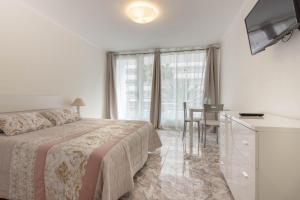a bedroom with a bed and a desk and a television at TENERIFE Olympia Apart Hotel-Playa de las Americas. Balcony, sea view & pool in Playa de las Americas