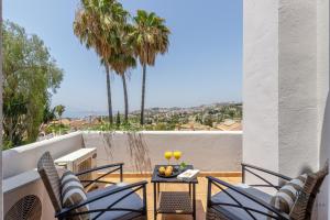 un patio con sedie e un tavolo sul balcone. di Living4malaga Villa Miraflores a Málaga