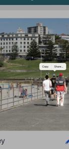 a group of people walking down a sidewalk near a beach at STUDIO IN BONDI in Sydney