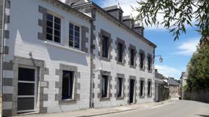 un edificio blanco con ventanas negras en una calle en La Villa Audren Love Room Jacuzzi en Châtelaudren