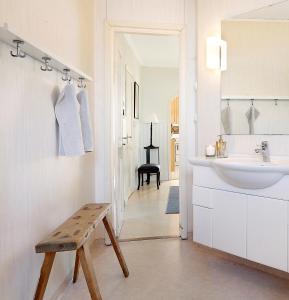 een witte badkamer met een wastafel en een houten bank bij Kallaxgårdshotel/apartment, Luleå in Luleå