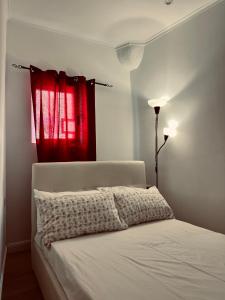 1 dormitorio con cama blanca y cortina roja en Comfort La tombola tripla deluxe en Nápoles