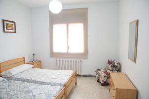 1 dormitorio con 2 camas, silla y ventana en Ca l'Armengol, en Balaguer