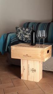 una botella de vino y copas en una mesa de madera en Casa Adua, en Donoratico