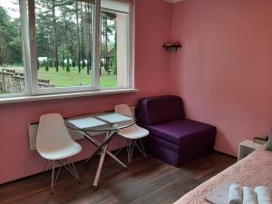 um quarto com uma cadeira roxa, uma mesa e uma janela em Apartmani Krcmarica 10 em Divčibare