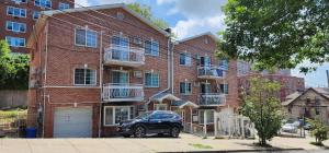 un coche negro estacionado frente a un edificio de ladrillo en Modern 2BR Apartment Jamaica Queens NYC, en Hillside